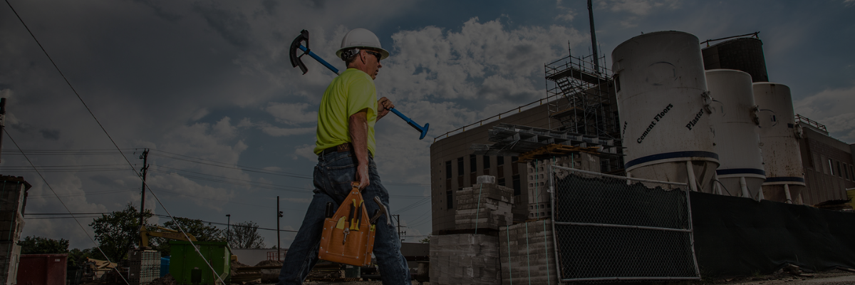 Man walking on job site holding IDEAL bender and tool bag 